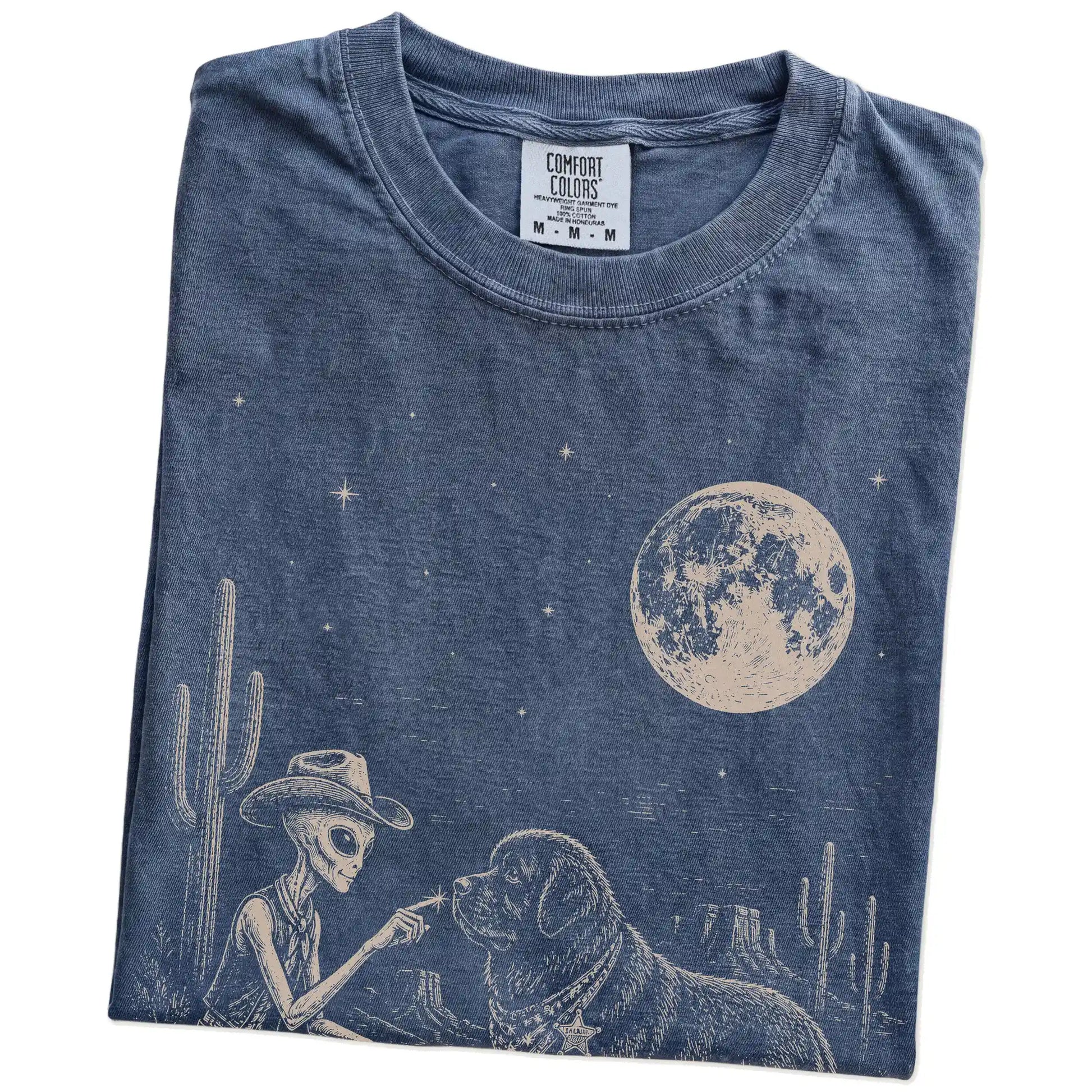 Folded Denim Comfort Colors® T-shirt showing cowboy alien fist-bumping a newfie beneath the moon