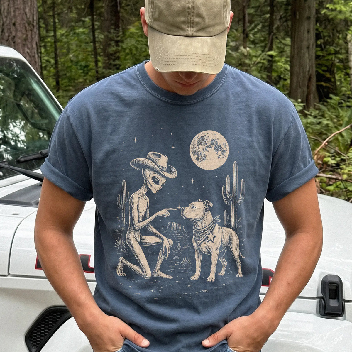 Model wearing a Denim Comfort Colors® T-shirt with cowboy alien fist-bumping a pitbull beneath the moon