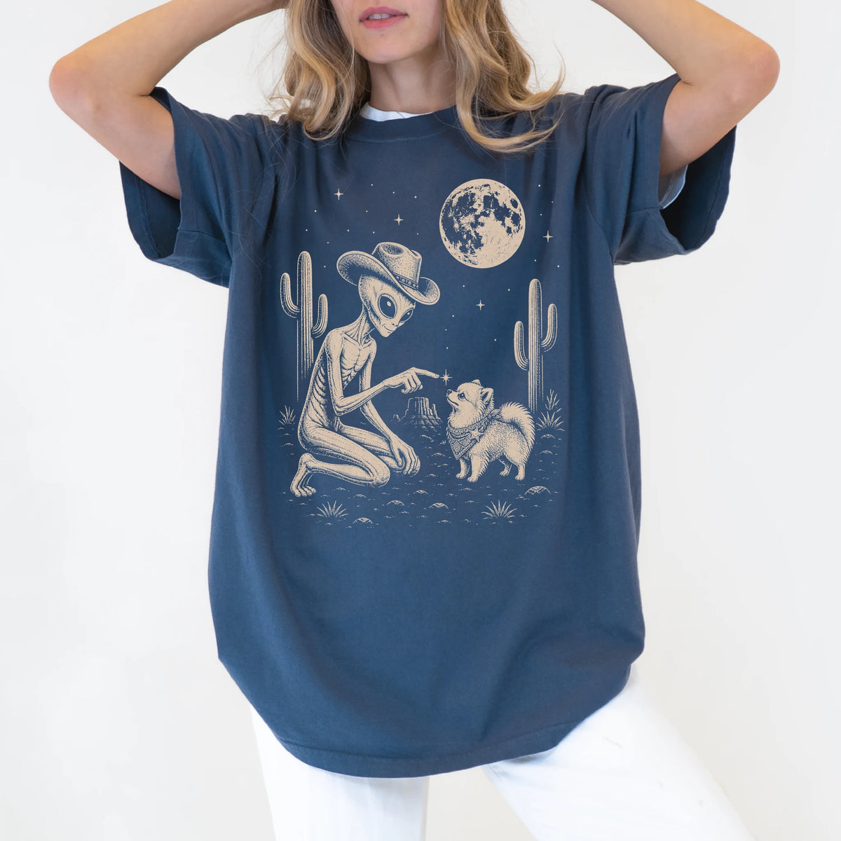 Model wearing a Denim Comfort Colors® T-shirt with cowboy alien fist-bumping a pomeranian beneath the moon