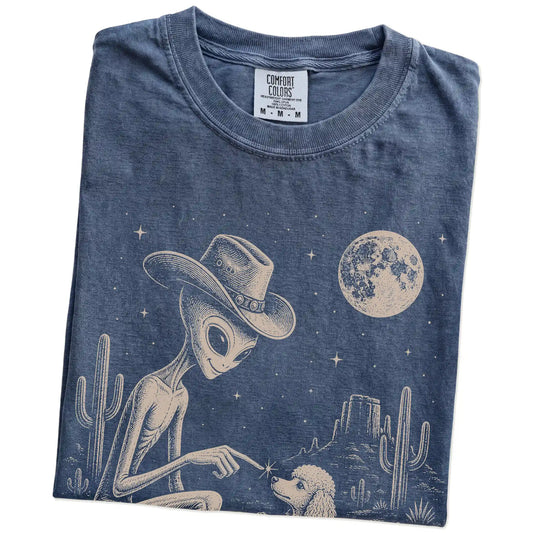 Folded Denim Comfort Colors® T-shirt showing cowboy alien fist-bumping a poodle beneath the moon