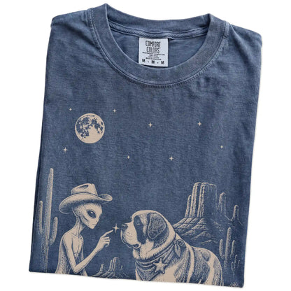 Folded Denim Comfort Colors® T-shirt showing cowboy alien fist-bumping a saint bernard beneath the moon