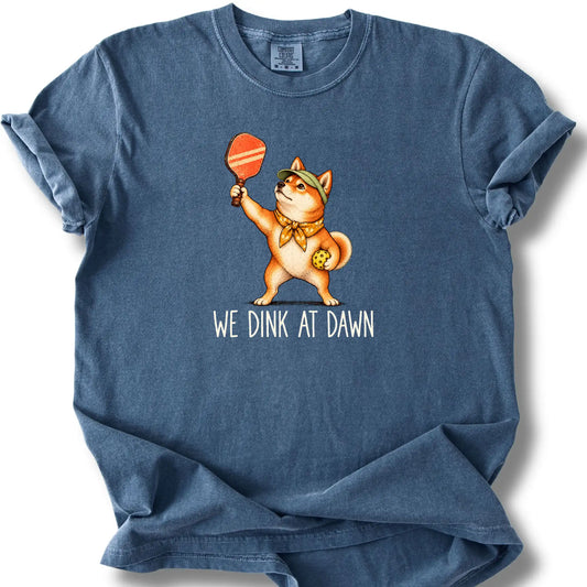 Shiba Inu with a pickleball paddle and ball on a Denim Comfort Colors® T-shirt with We Dink at Dawn text