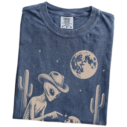 Folded Denim Comfort Colors® T-shirt showing cowboy alien fist-bumping a shih tzu beneath the moon