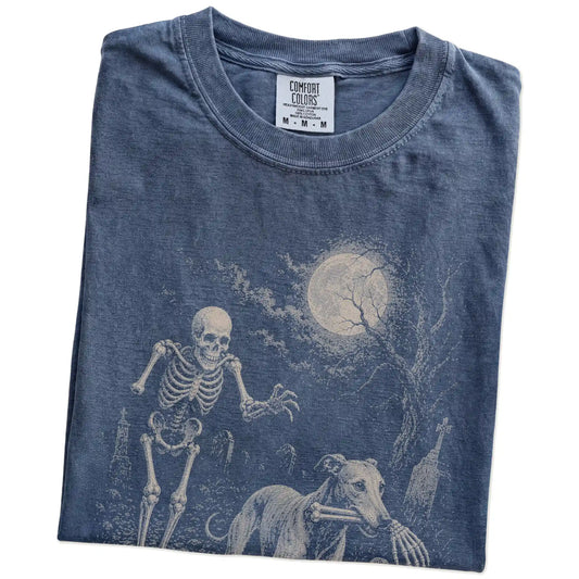 Folded denim T-shirt with a Greyhound carrying a skeleton arm through a graveyard.