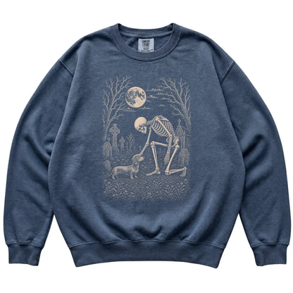 Skeleton petting a Dachshund in a graveyard on a Denim sweatshirt