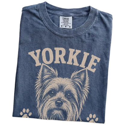 Folded Denim Comfort Colors® T-shirt showing Yorkie design with “Small, But Running The Meeting” lettering