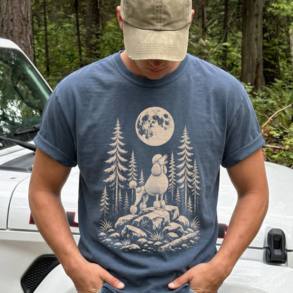 Model wearing a Denim Comfort Colors® T-shirt with a Standard Poodle howling beneath the moon and pine trees