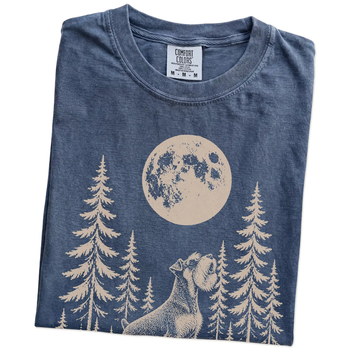 Folded Denim Comfort Colors® T-shirt showing a Standard Schnauzer howling beneath the moon and pine trees