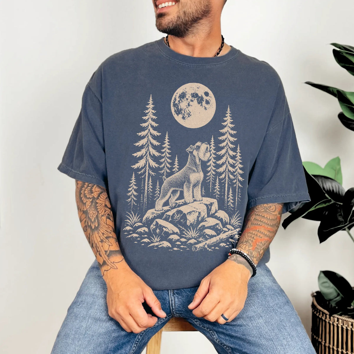 Model wearing a Denim Comfort Colors® T-shirt with a Standard Schnauzer howling beneath the moon and pine trees