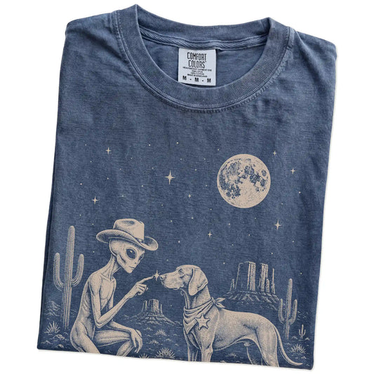 Folded Denim Comfort Colors® T-shirt showing cowboy alien fist-bumping a weimaraner beneath the moon