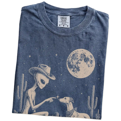 Folded Denim Comfort Colors® T-shirt showing cowboy alien fist-bumping a whippet beneath the moon