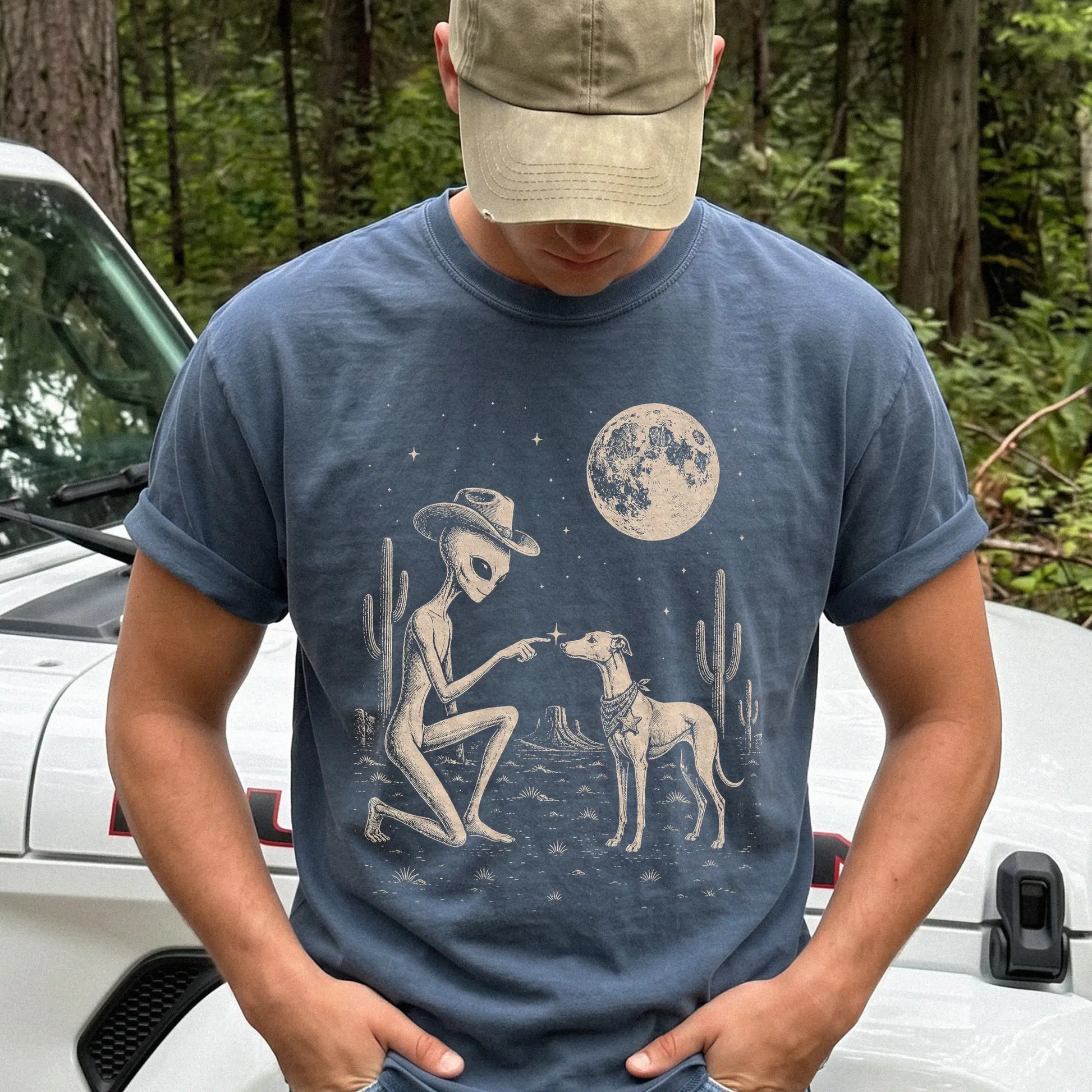 Model wearing a Denim Comfort Colors® T-shirt with cowboy alien fist-bumping a whippet beneath the moon