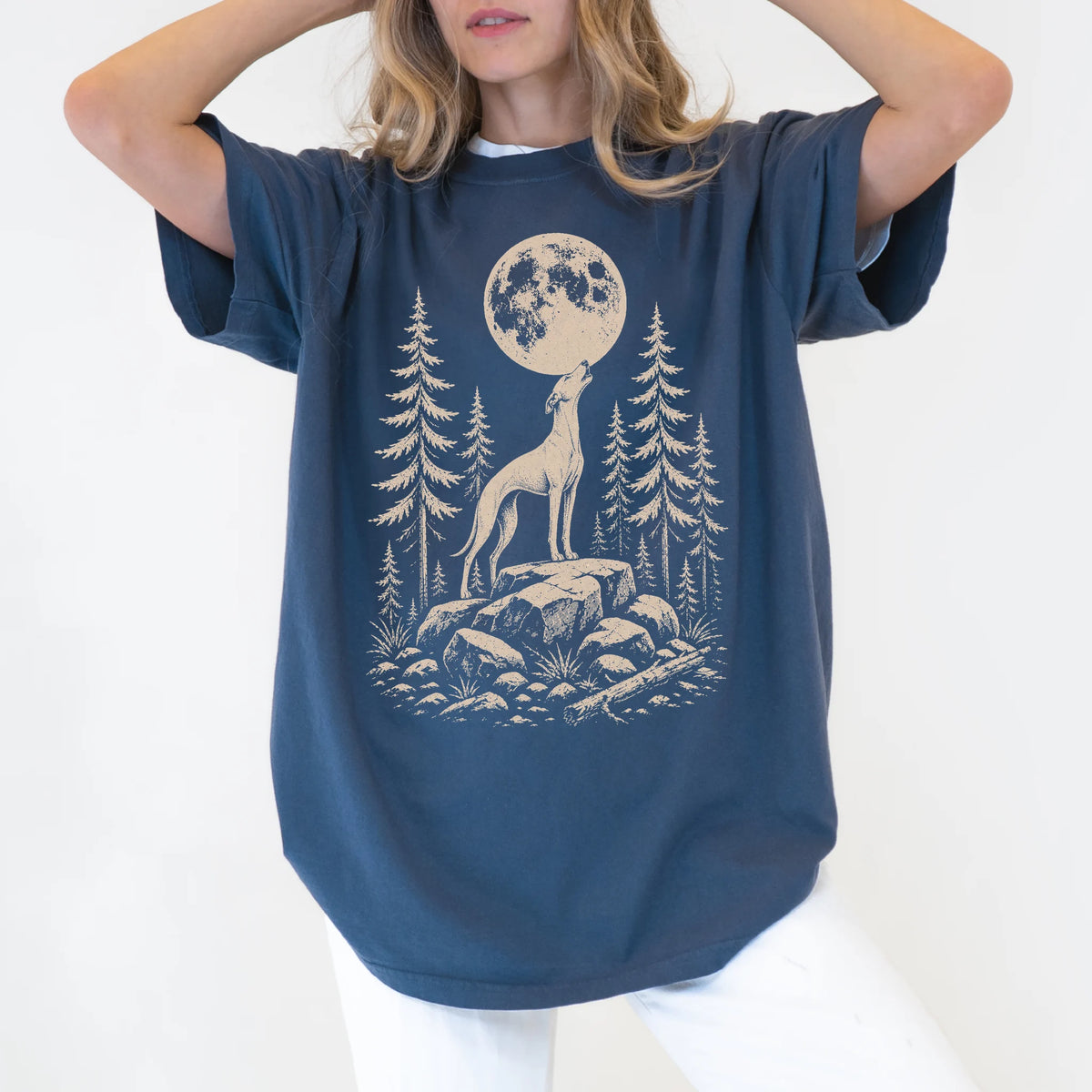 Model wearing a Denim Comfort Colors® T-shirt with a Whippet howling beneath the moon and pine trees