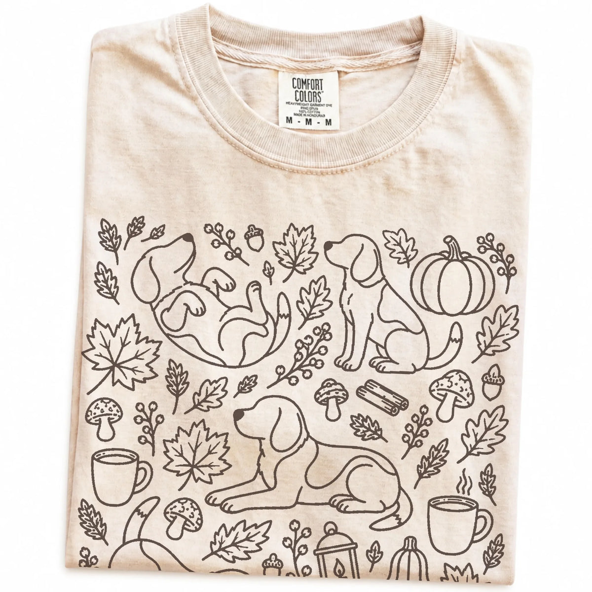 Folded Ivory Comfort Colors® T-shirt showing Beagle dogs with pumpkins, leaves, acorns, and woodland details