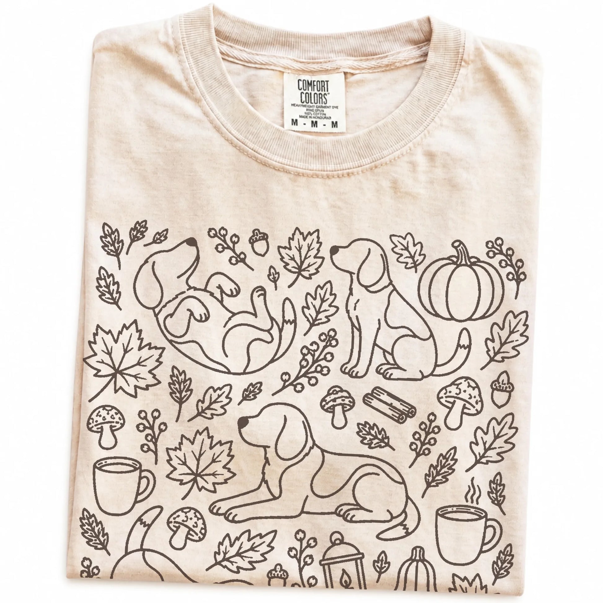 Folded Ivory Comfort Colors® T-shirt showing Beagle dogs with pumpkins, leaves, acorns, and woodland details
