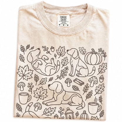 Folded Ivory Comfort Colors® T-shirt showing Beagle dogs with pumpkins, leaves, acorns, and woodland details