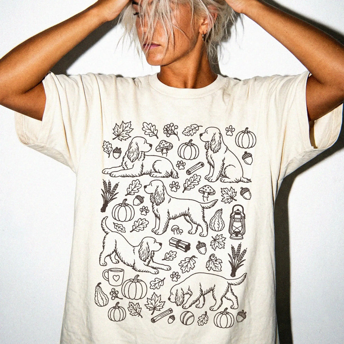 Model wearing a Ivory Comfort Colors® T-shirt with Cocker Spaniel dogs with pumpkins, leaves, acorns, and woodland details