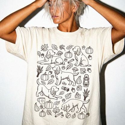Model wearing a Ivory Comfort Colors® T-shirt with Cocker Spaniel dogs with pumpkins, leaves, acorns, and woodland details