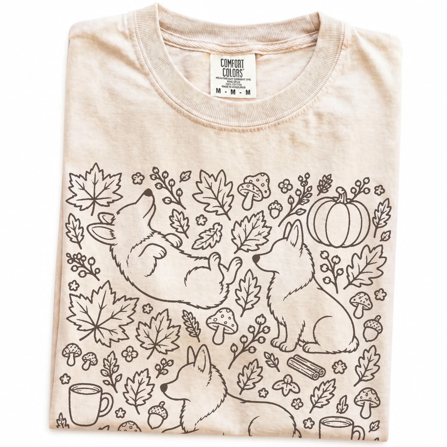 Folded Ivory Comfort Colors® T-shirt showing Corgi dogs with pumpkins, leaves, acorns, and woodland details
