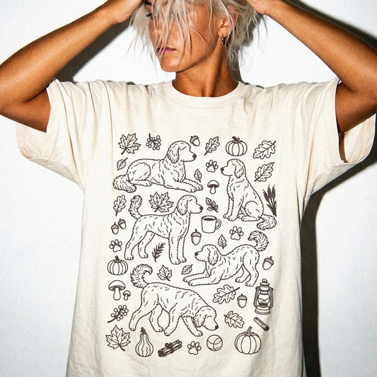 Model wearing a Ivory Comfort Colors® T-shirt with Goldendoodle dogs with pumpkins, leaves, acorns, and woodland details