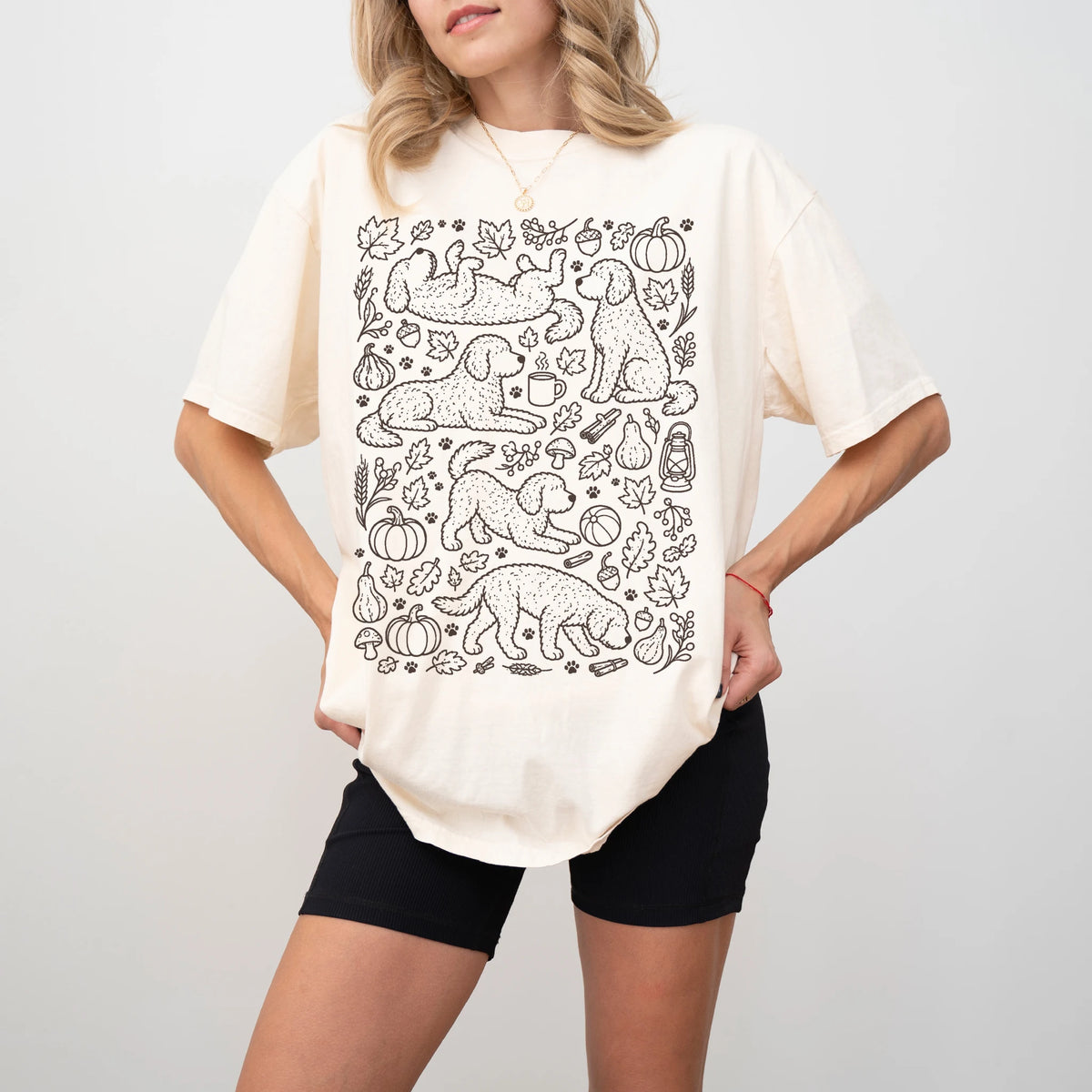 Model wearing a Ivory Comfort Colors® T-shirt with Labradoodle dogs with pumpkins, leaves, acorns, and woodland details