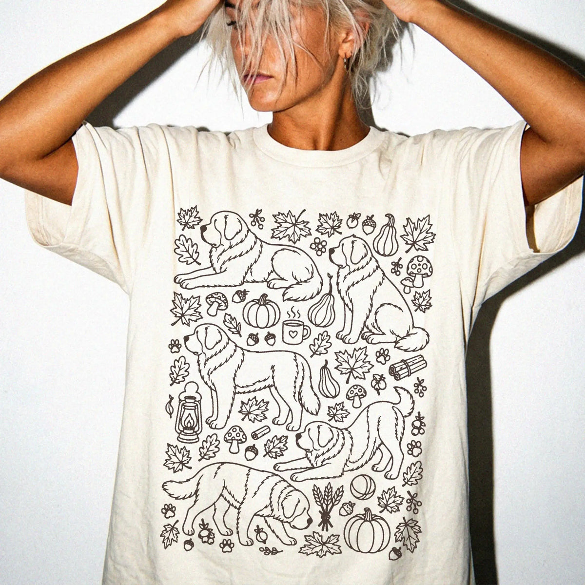 Model wearing a Ivory Comfort Colors® T-shirt with Saint Bernard dogs with pumpkins, leaves, acorns, and woodland details
