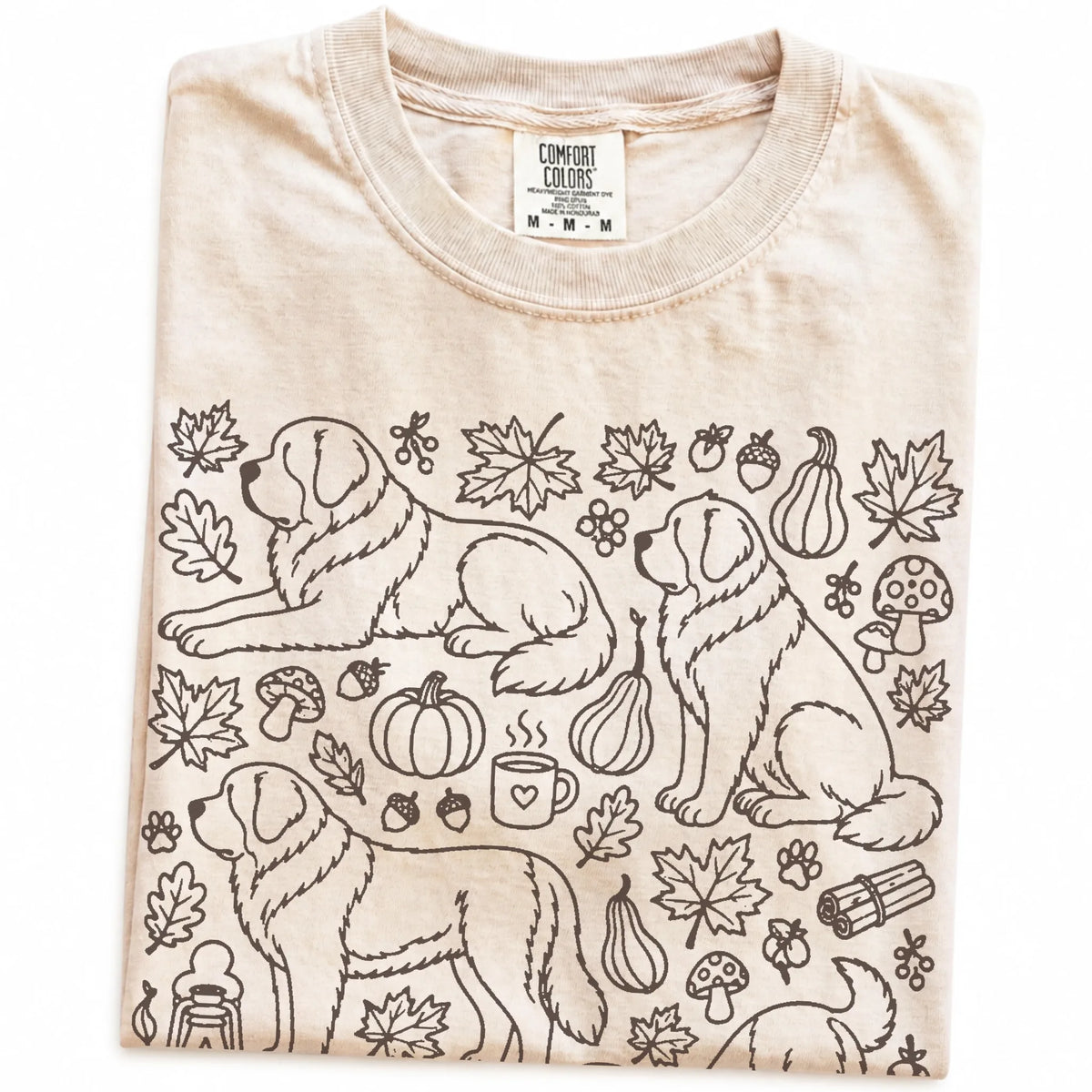 Folded Ivory Comfort Colors® T-shirt showing Saint Bernard dogs with pumpkins, leaves, acorns, and woodland details