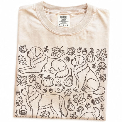 Folded Ivory Comfort Colors® T-shirt showing Saint Bernard dogs with pumpkins, leaves, acorns, and woodland details