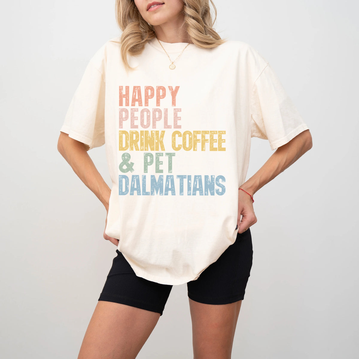 Model wearing a Ivory Comfort Colors® T-shirt featuring Dalmatian with coffee and “Happy People Drink Coffee and Pet Dogs” le
