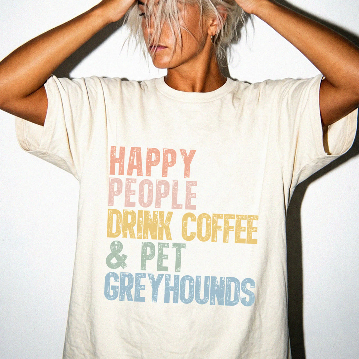 Model wearing a Ivory Comfort Colors® T-shirt featuring Greyhound with coffee and “Happy People Drink Coffee and Pet Dogs” le