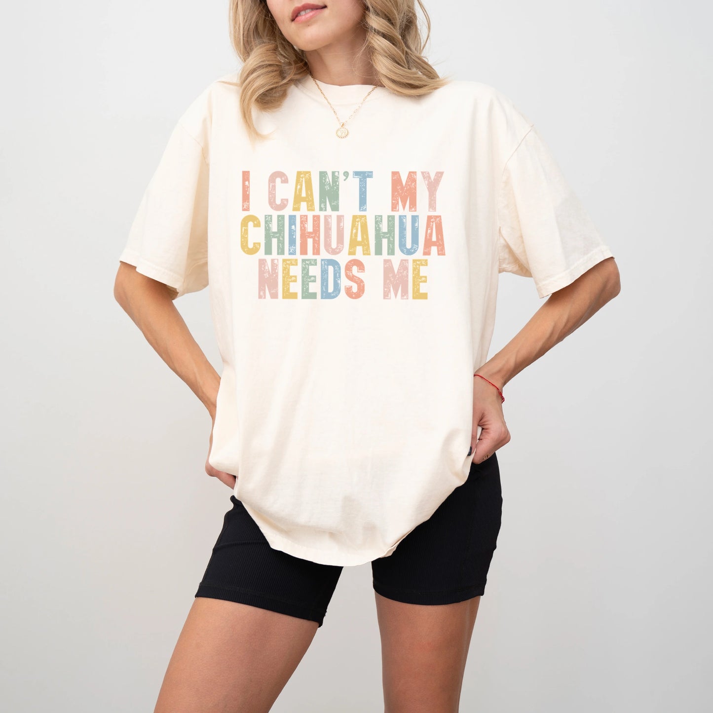 Model wearing a Ivory Comfort Colors® T-shirt featuring Chihuahua with “I Can’t, My Dog Needs Me” lettering
