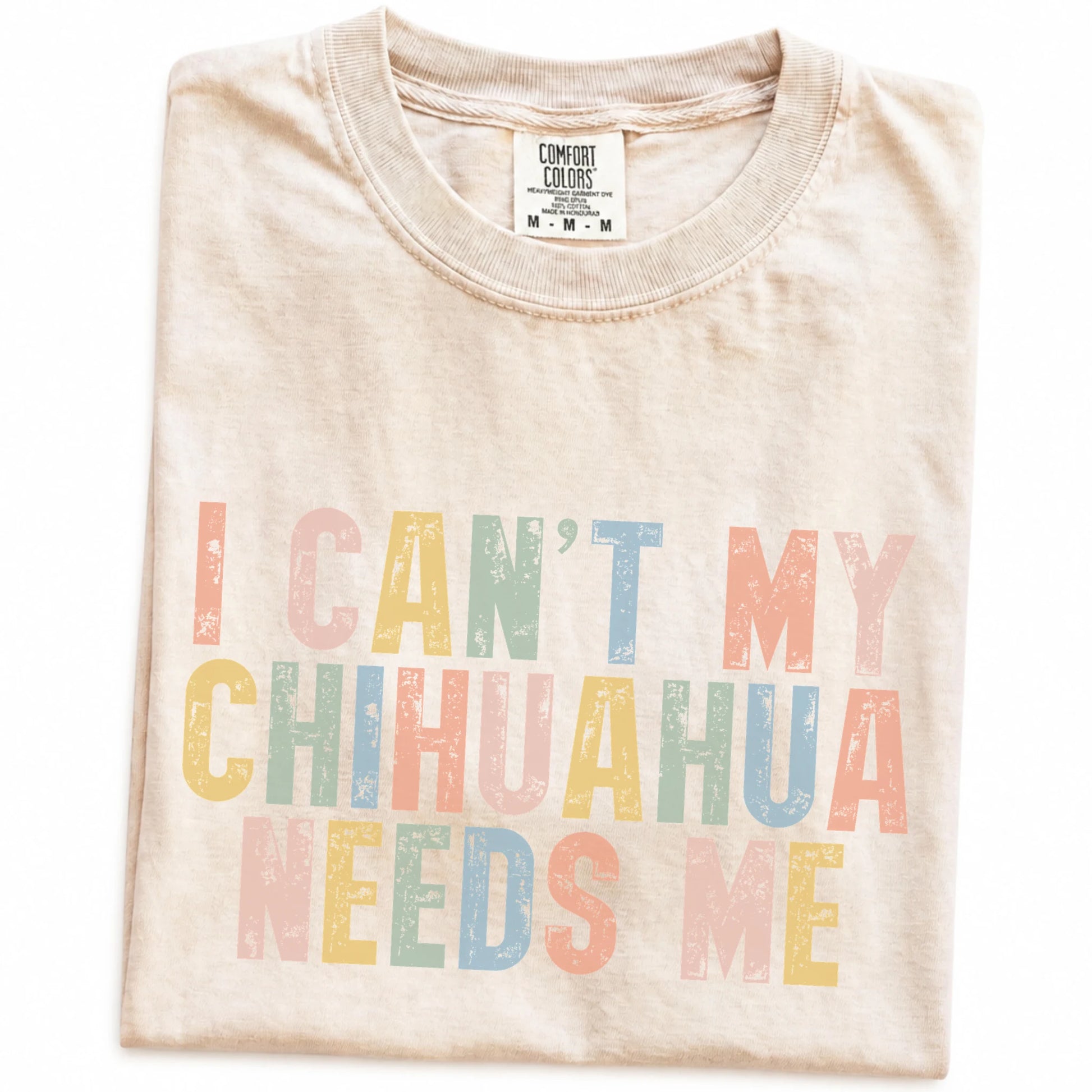 Folded Ivory Comfort Colors® T-shirt showing Chihuahua with “I Can’t, My Dog Needs Me” lettering