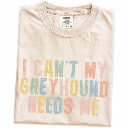 Folded Ivory Comfort Colors® T-shirt showing Greyhound with “I Can’t, My Dog Needs Me” lettering