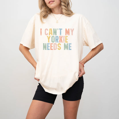 Model wearing a Ivory Comfort Colors® T-shirt featuring Yorkie with “I Can’t, My Dog Needs Me” lettering
