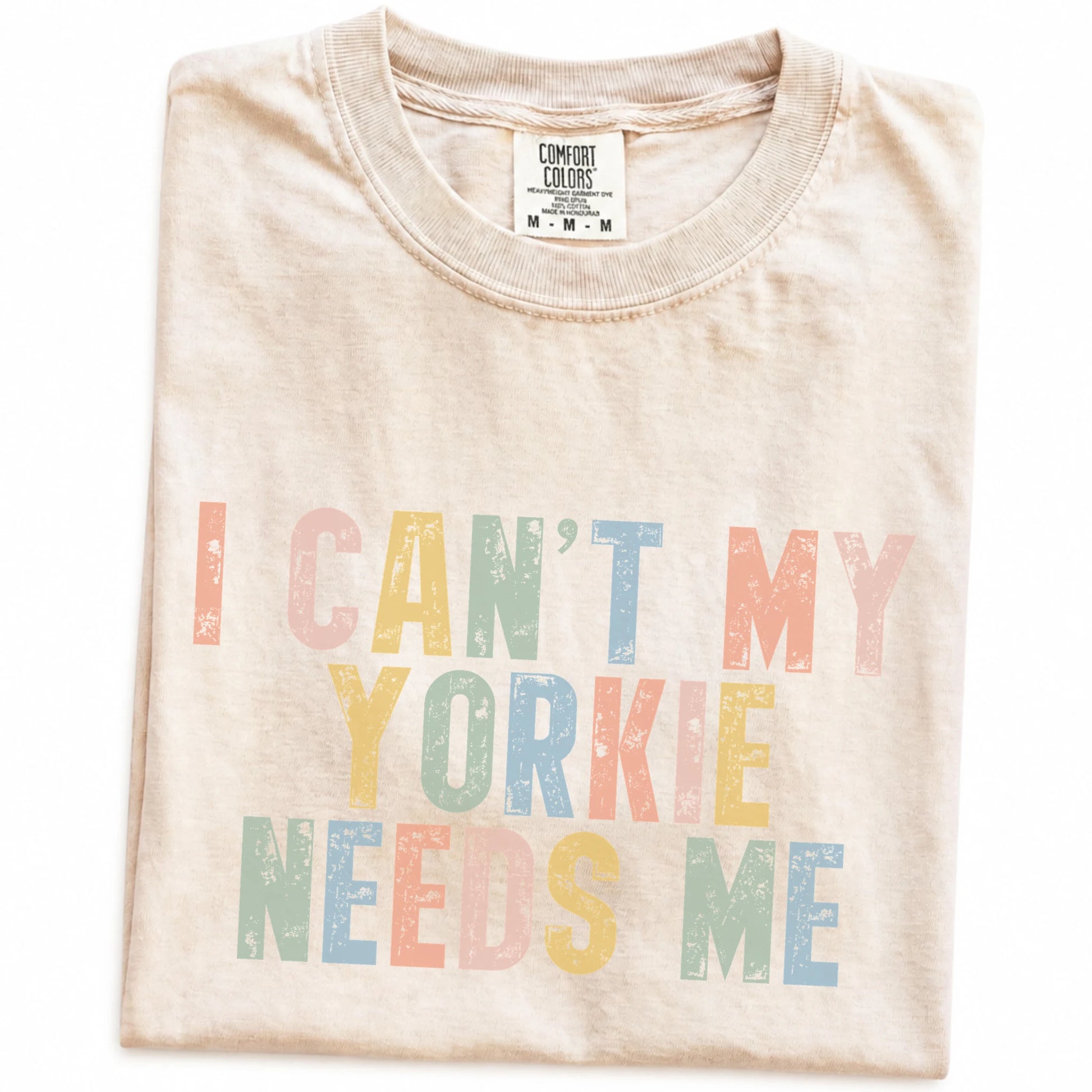 Folded Ivory Comfort Colors® T-shirt showing Yorkie with “I Can’t, My Dog Needs Me” lettering