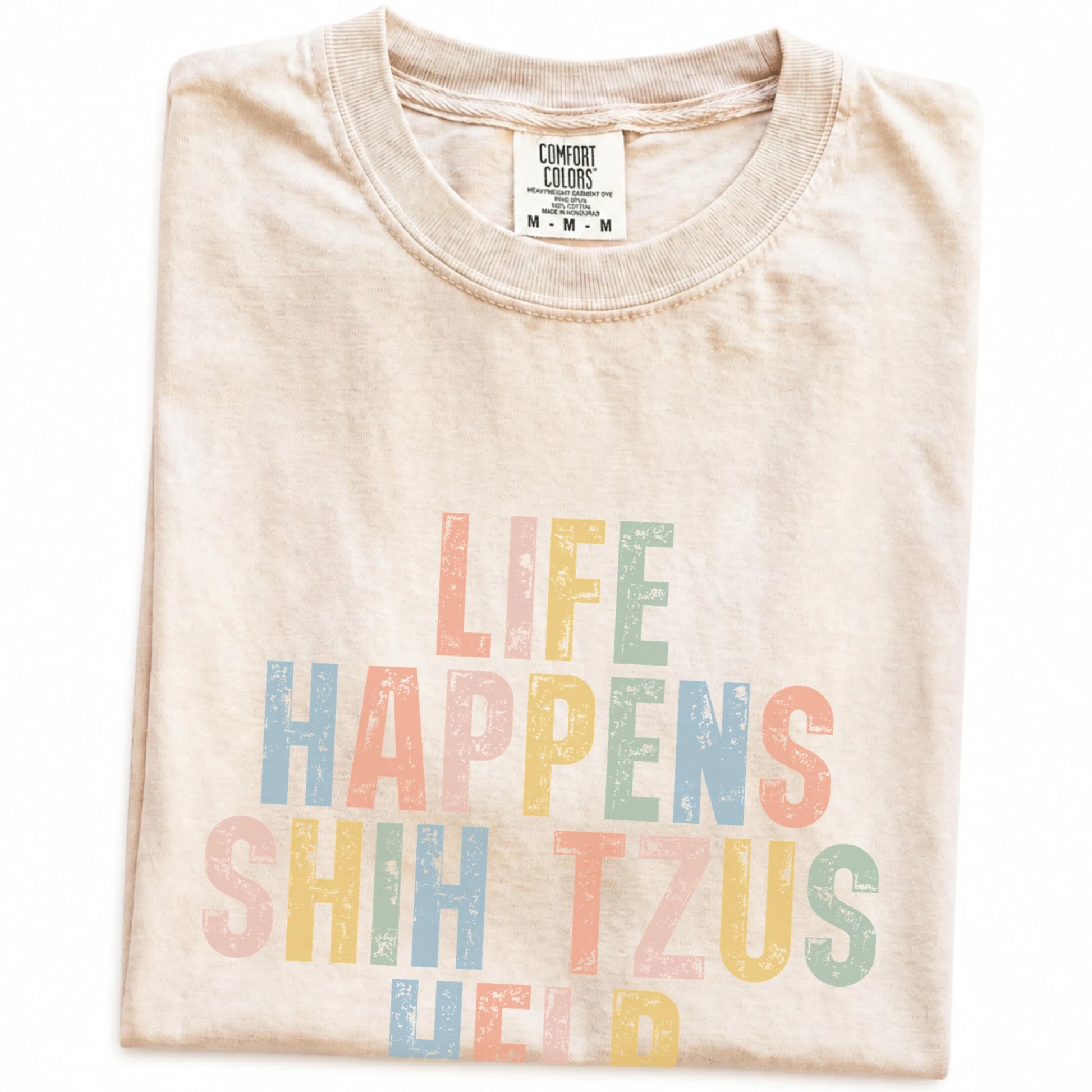 Folded Ivory Comfort Colors® T-shirt showing retro “Life Happens, Shih Tzus Help” lettering