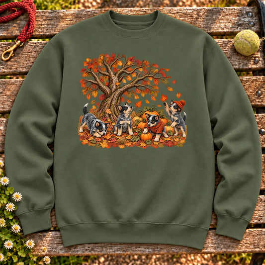 Four Blue Heeler puppies with pumpkins beneath an autumn tree on a Military Green crewneck sweatshirt