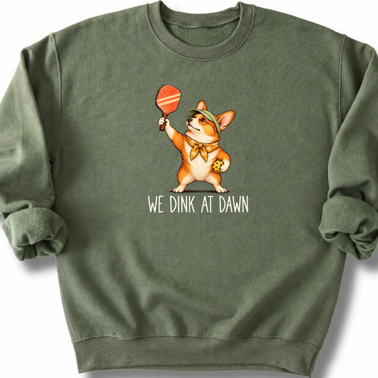 Corgi with a pickleball paddle and ball on a Military Green Gildan® sweatshirt with We Dink at Dawn text