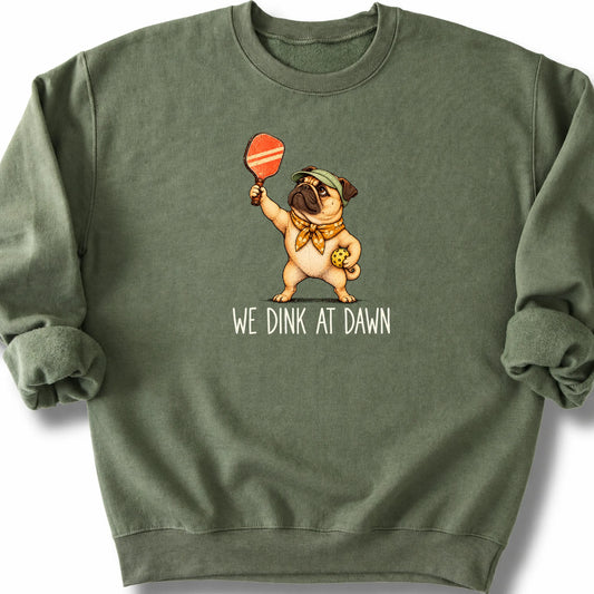 Pug with a pickleball paddle and ball on a Military Green Gildan® sweatshirt with We Dink at Dawn text