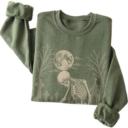 Folded Military Green sweatshirt with a skeleton petting a Shih Tzu in a graveyard