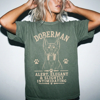 Model wearing a Moss Comfort Colors® T-shirt featuring Doberman design with “Alert, Elegant & Slightly Intimidating” letterin