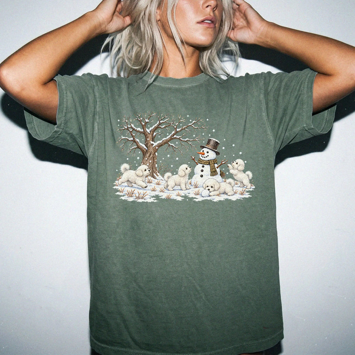 Bichon Frise puppies playing in snow with a snowman on a Moss T-shirt worn by a model