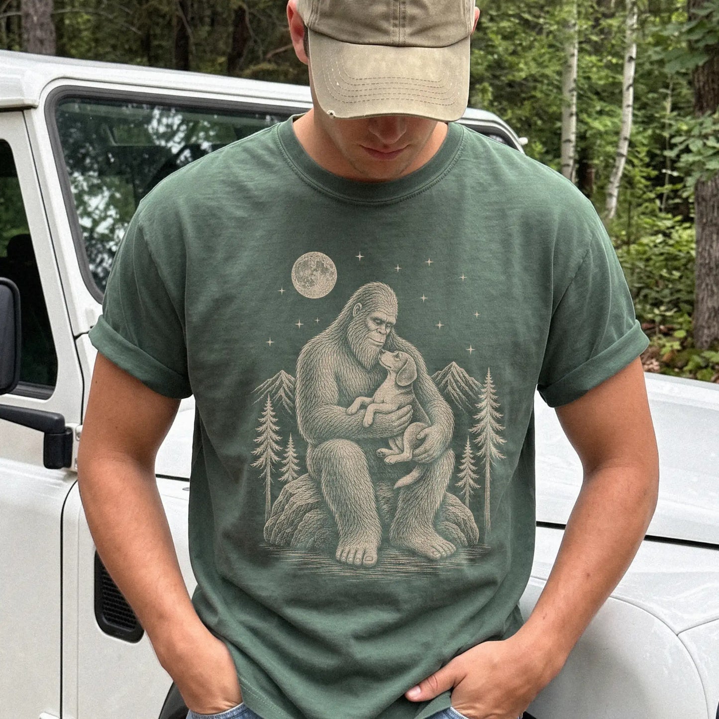 Model wearing a Moss Comfort Colors® T-shirt showing Bigfoot holding a Beagle