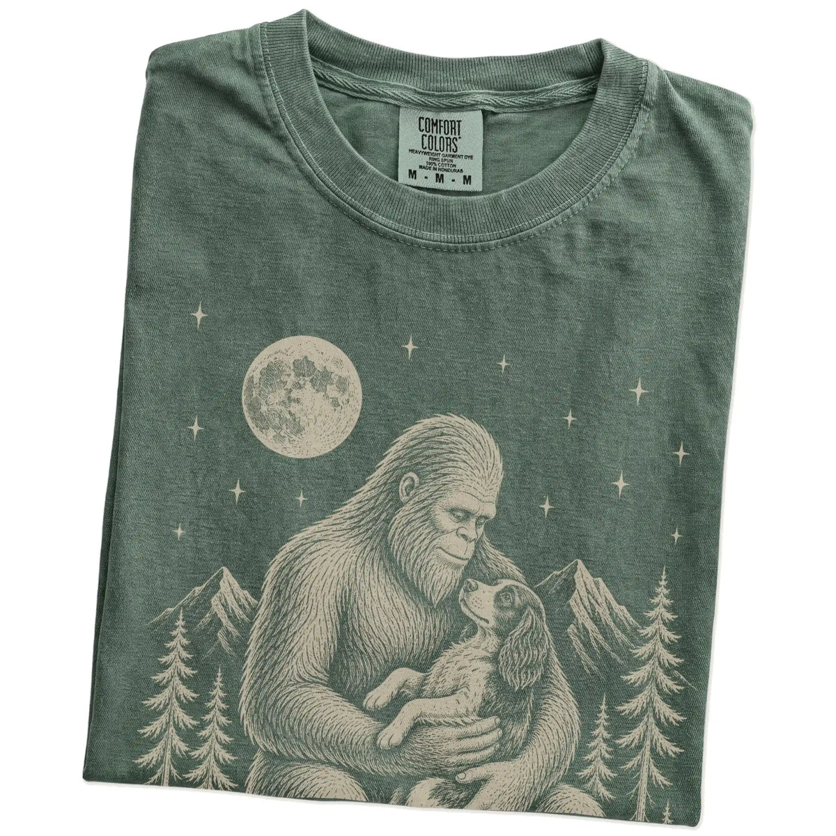 Folded Moss Comfort Colors® T-shirt showing Bigfoot holding a Springer Spaniel