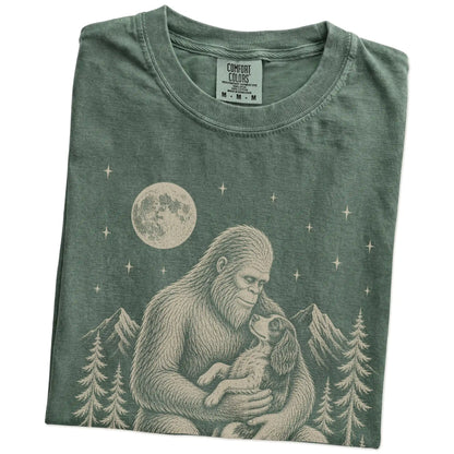 Folded Moss Comfort Colors® T-shirt showing Bigfoot holding a Springer Spaniel