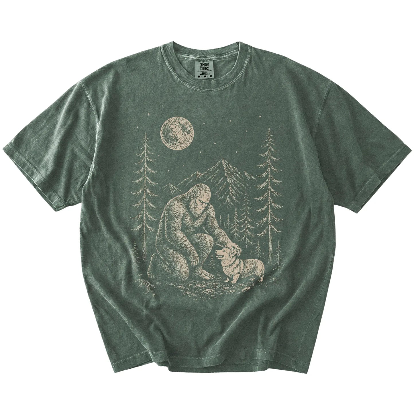 Bigfoot petting a Corgi beneath the moon in a pine forest on a Moss Comfort Colors® T-shirt