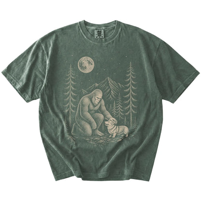 Bigfoot petting a Corgi beneath the moon in a pine forest on a Moss Comfort Colors® T-shirt
