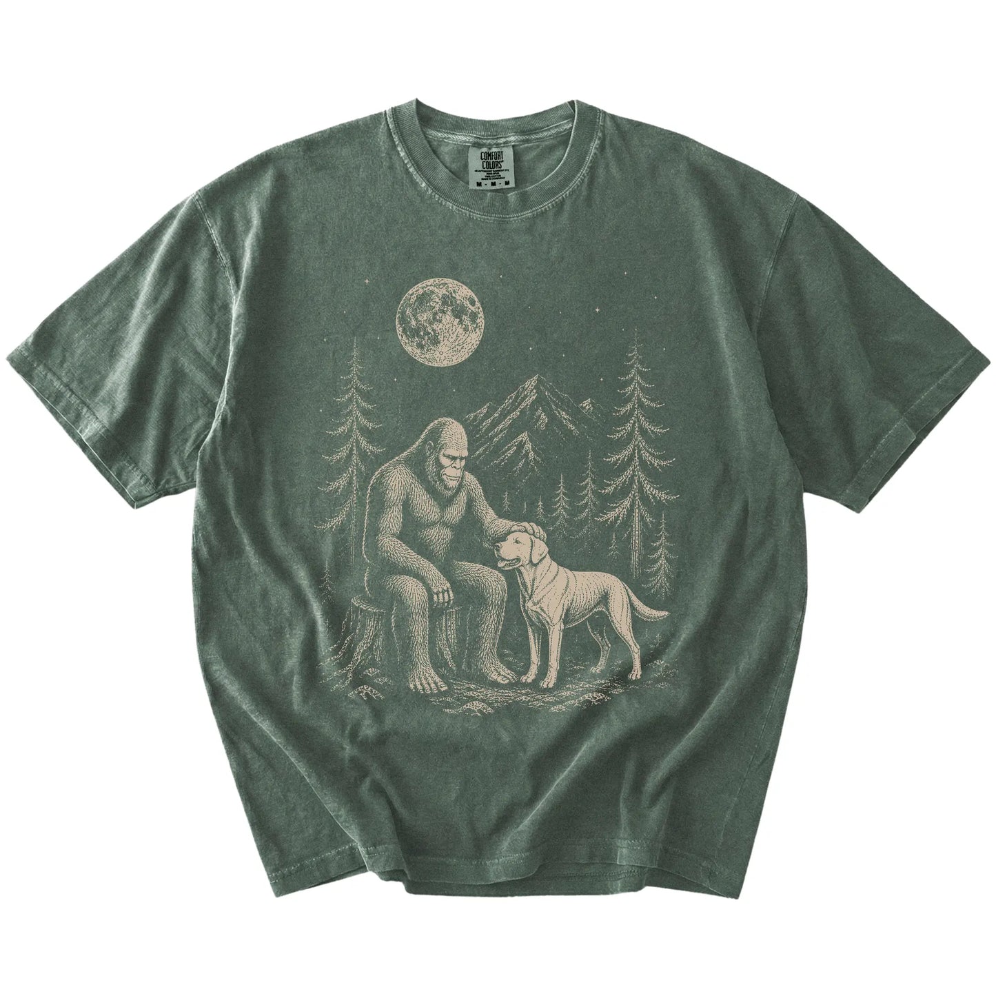 Bigfoot petting a Labrador Retriever beneath the moon in a pine forest on a Moss Comfort Colors® T-shirt