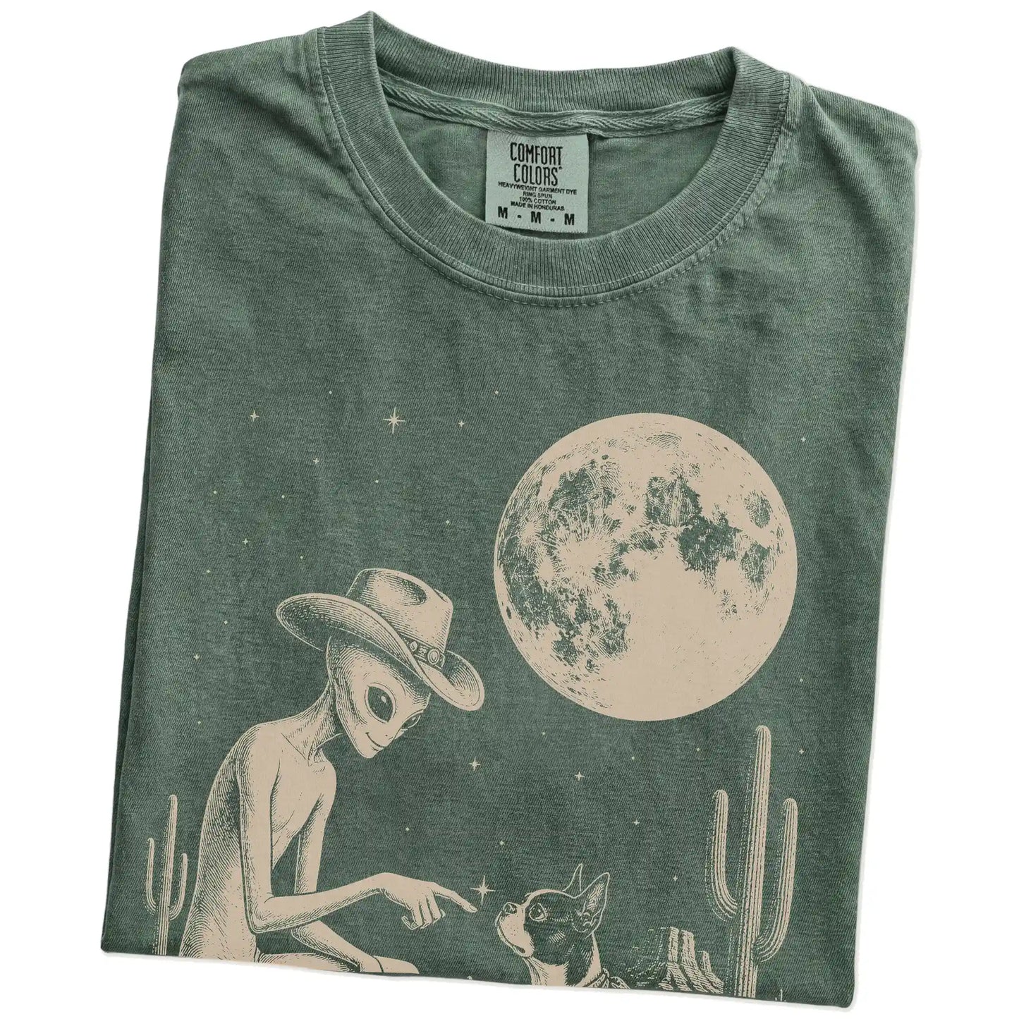 Folded Moss Comfort Colors® T-shirt showing cowboy alien fist-bumping a boston terrier beneath the moon
