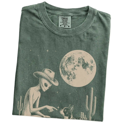 Folded Moss Comfort Colors® T-shirt showing cowboy alien fist-bumping a boston terrier beneath the moon